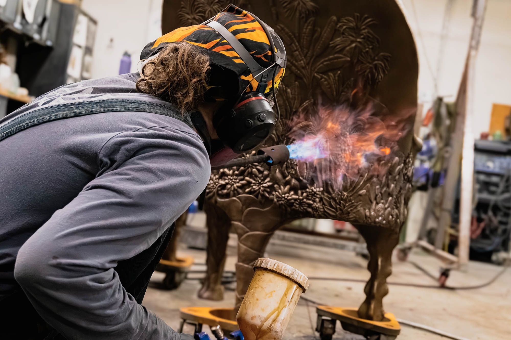 An artisan applies a chemical patina to a bronze sculpture.