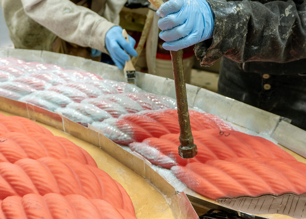 Creating a rubber mold of the rapid prototype. An artisan is spraying the rubber over the form with gloved hands.