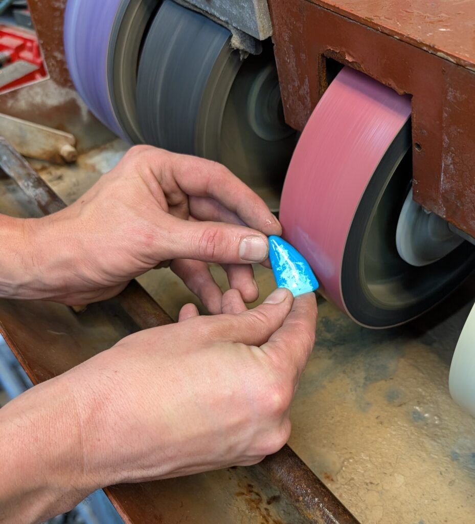 James holding a vibrant blue opal to a polishing wheel.