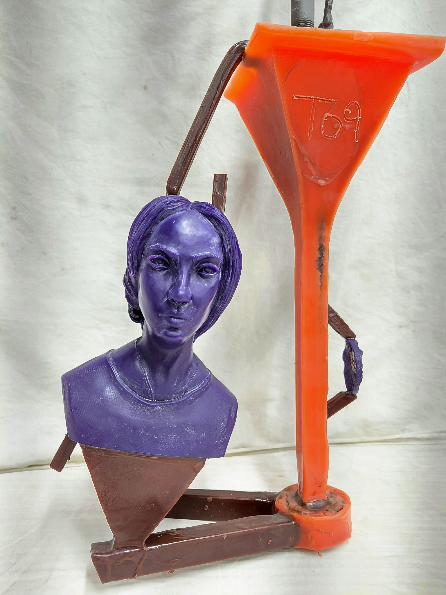 The castable 3D print of a woman has been attached to a gating system, rods of wax attach it to a cup that is structured to guide the flow of molten bronze.